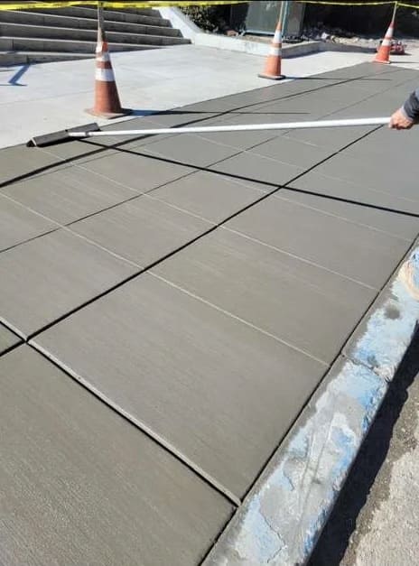 Broom finished concrete sidewalk installation with straight tooled control joints and curb