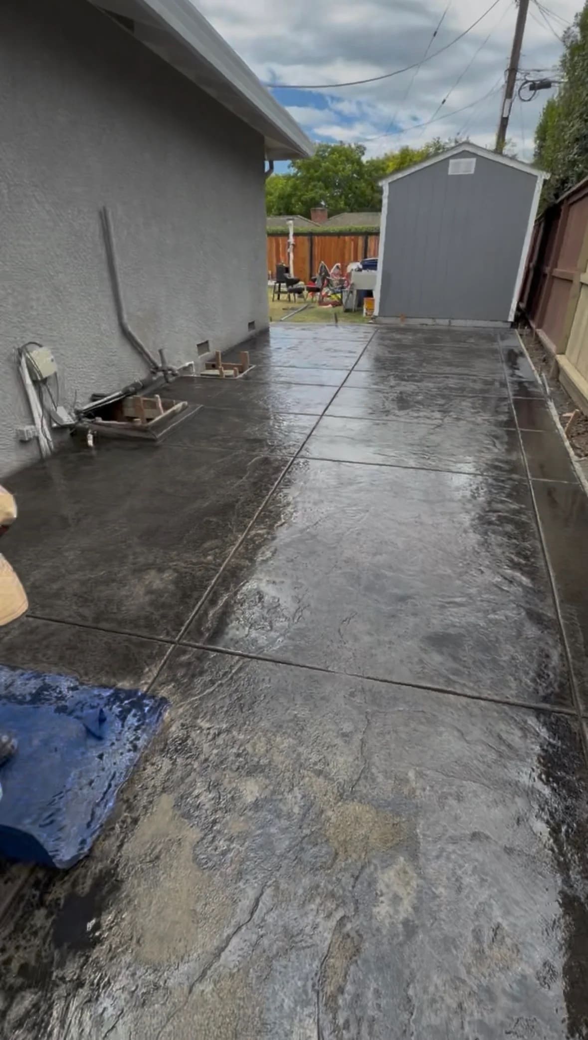 Charcoal stamped concrete patio slab with custom stone slate texture along residential home