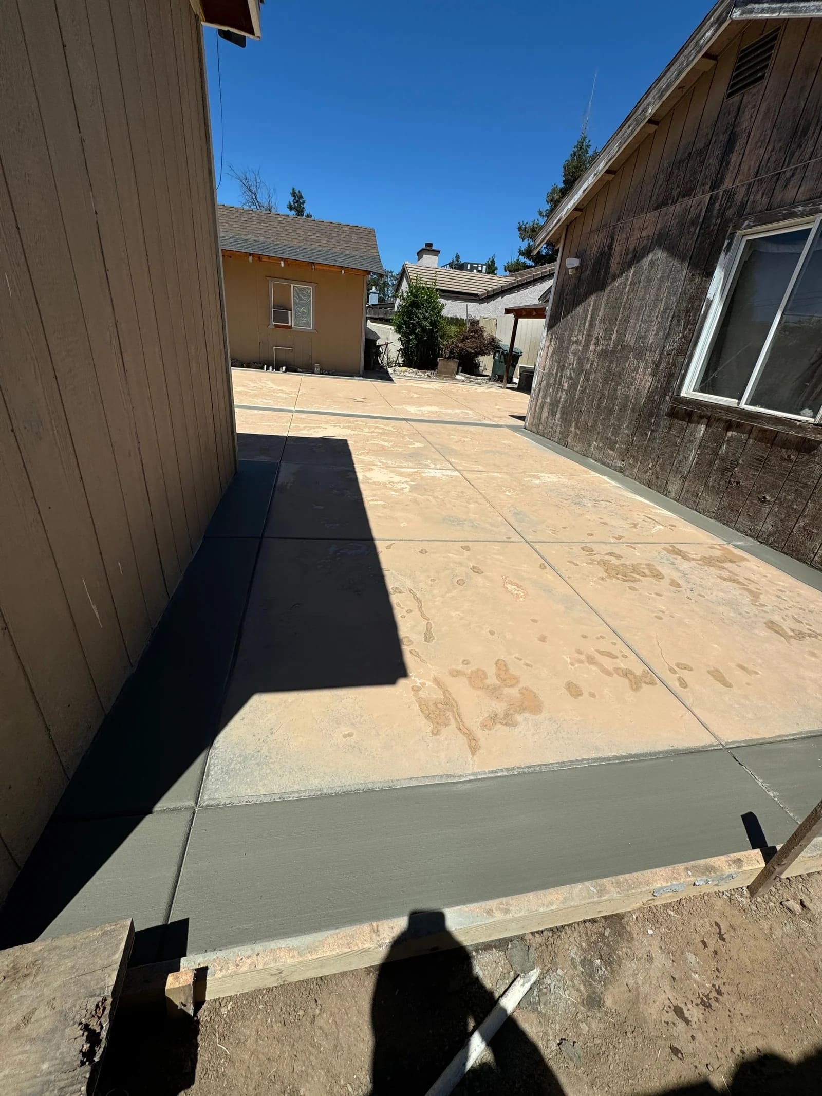 Colored concrete patio flatwork with contrasting broom finished border between residential structures