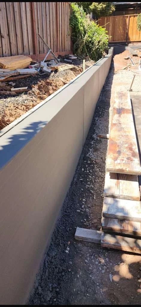 Poured concrete retaining wall along residential grade and fence line
