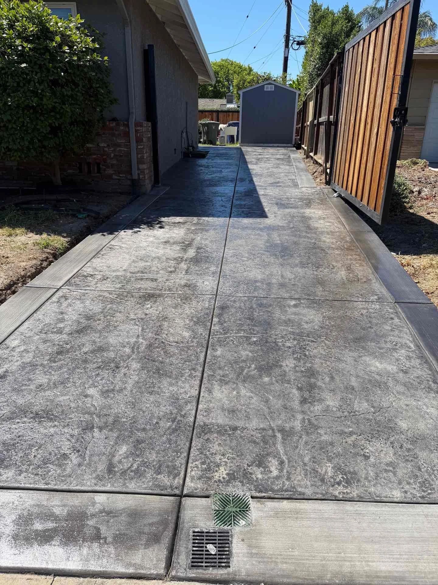 Finished stamped concrete side driveway with bordered edges and integrated drainage