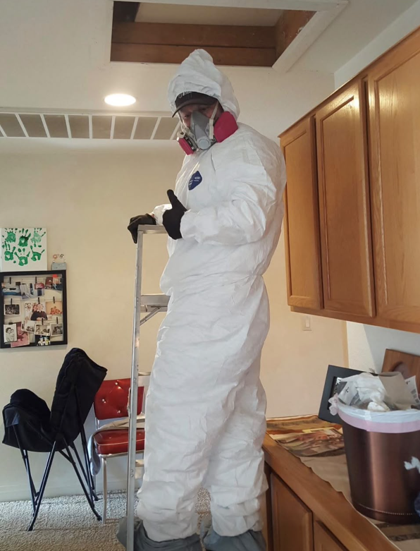 Technician in full PPE and respirator preparing for attic decontamination