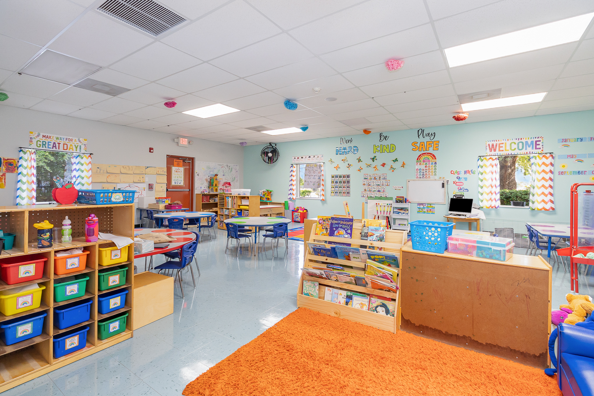 Preschool classroom with learning centers, art supplies, a circle time rug, and small chairs