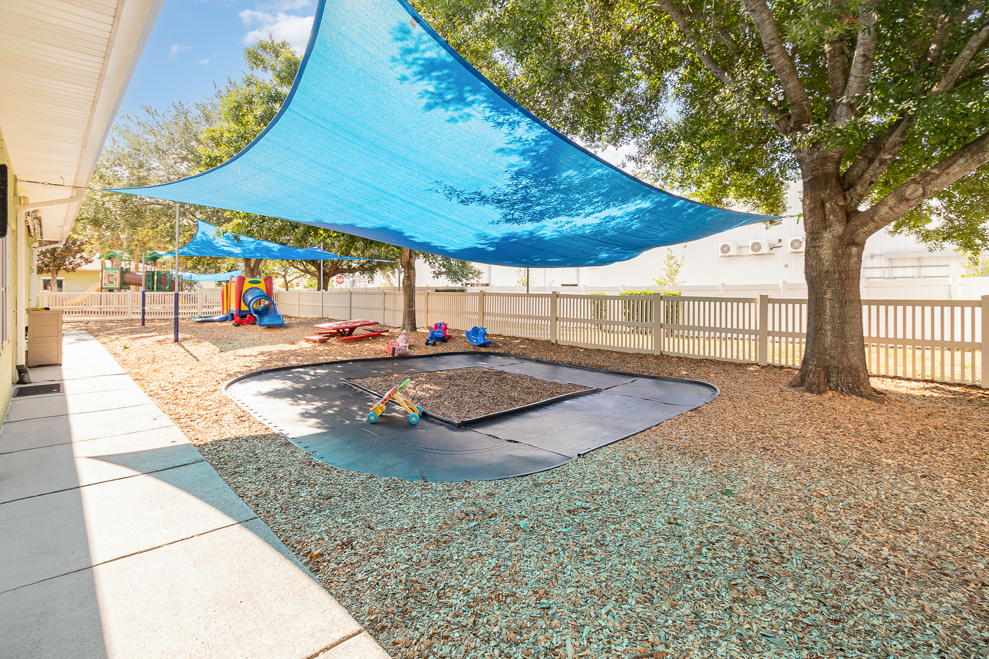 Summer camp scene with outdoor games, an arts and crafts table, and sports equipment on a sunny playground