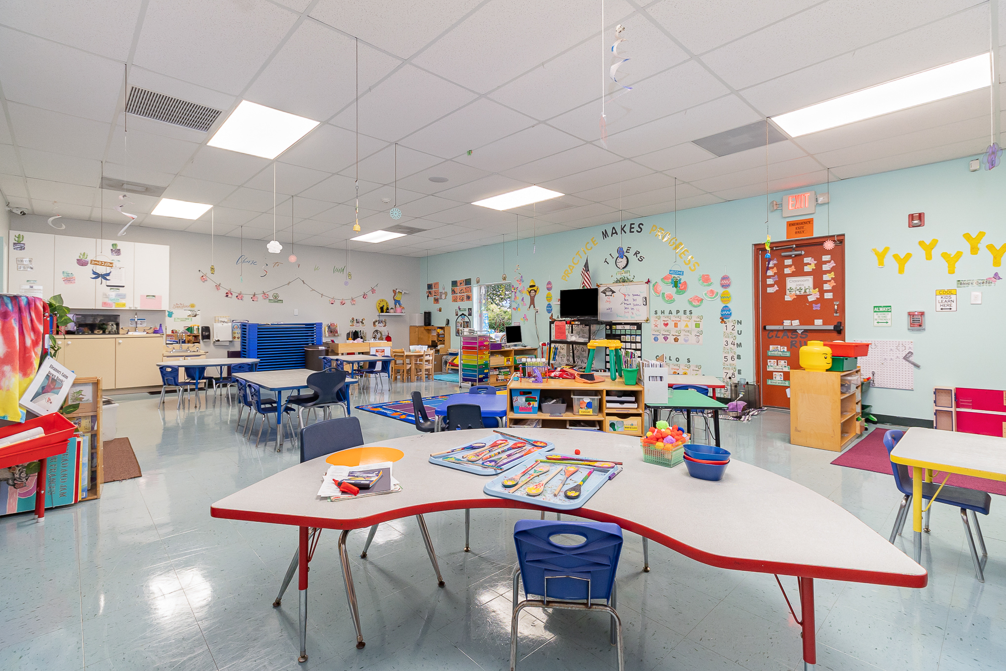A preschool classroom with learning centers, art supplies, and a circle time rug