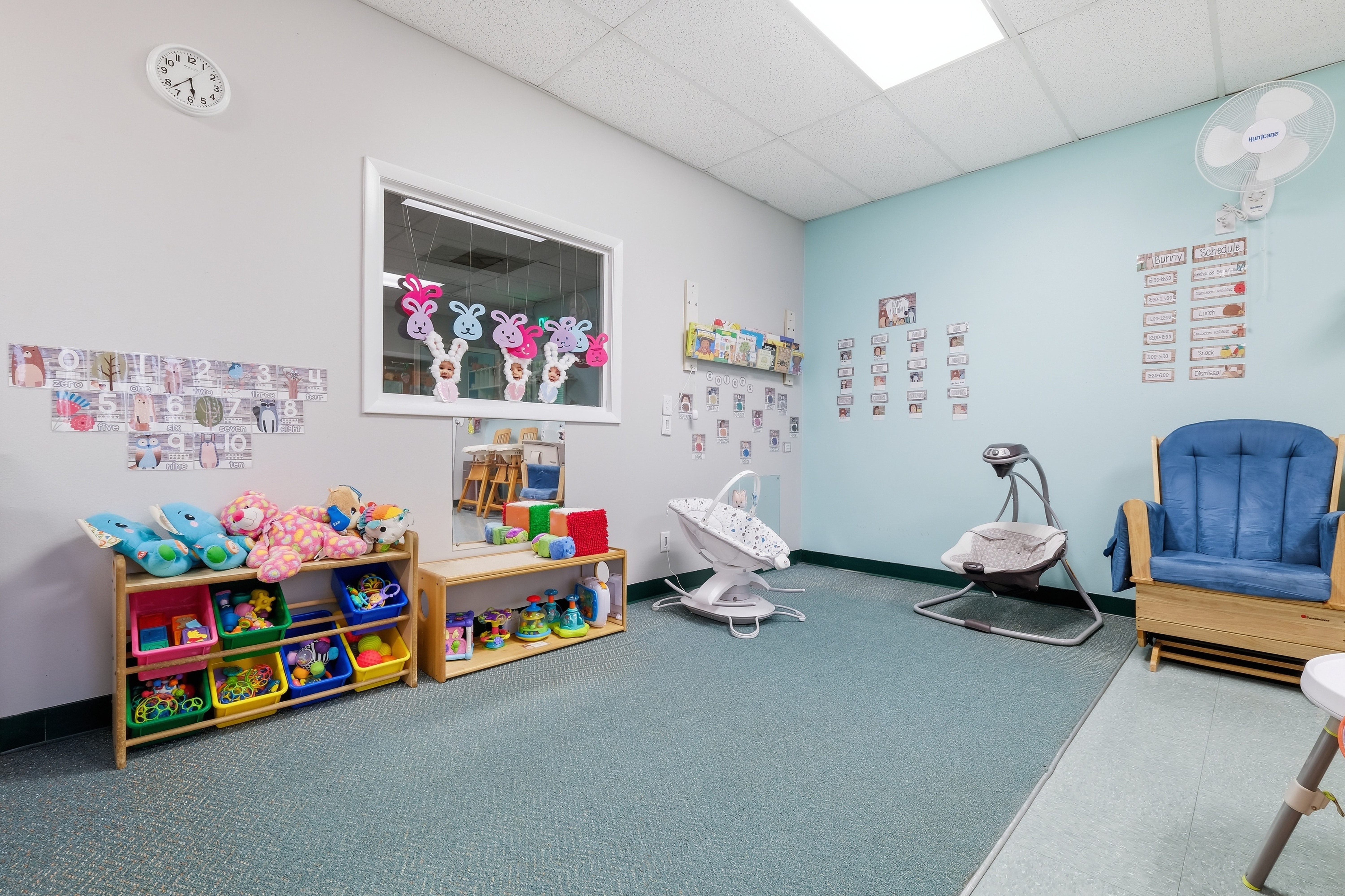 Calm infant room with low cribs, a rocking chair, and a soft play mat in warm natural light