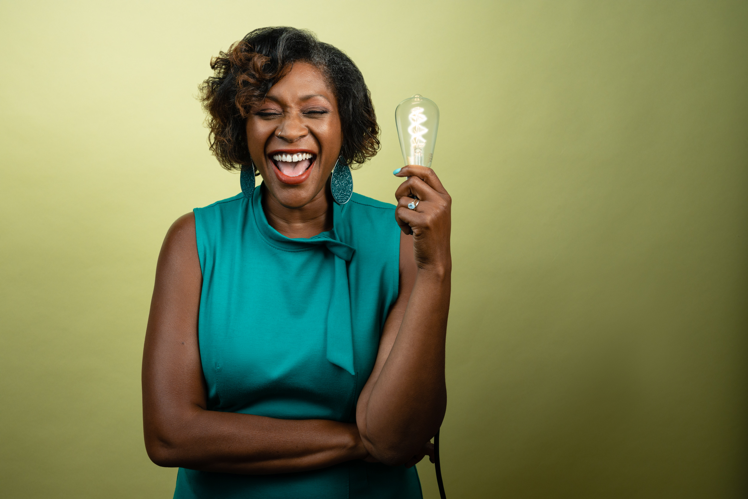 Dasha Kelly smiling joyfully and holding an illuminated lightbulb