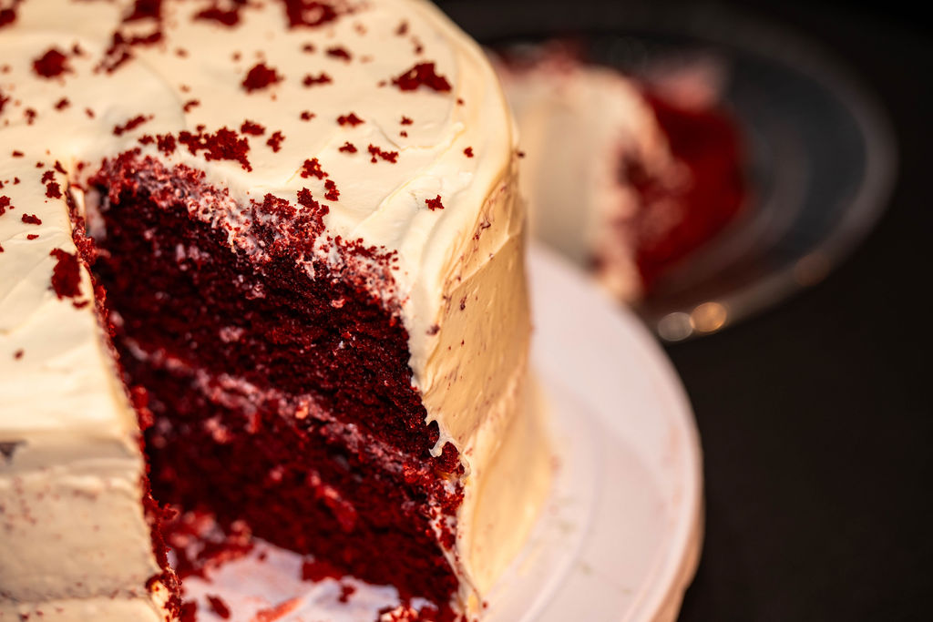 Freshly cut slice of red velvet cake with cream cheese frosting