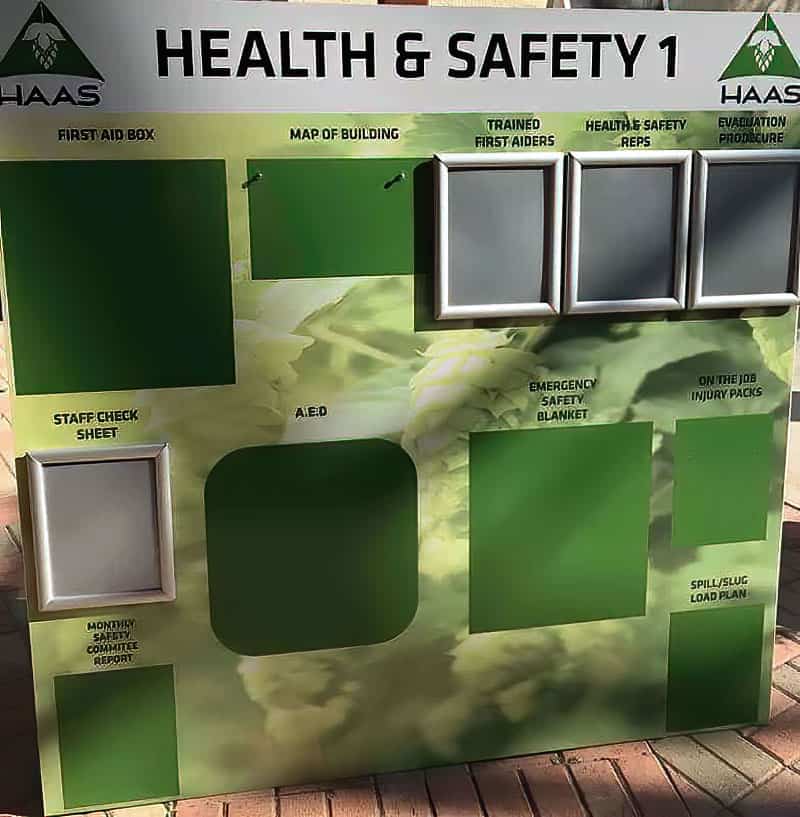 Haas Health and Safety 1 visual safety management board with aluminum snap frames and designated spaces for first aid box, AED, emergency blanket, and building evacuation plan