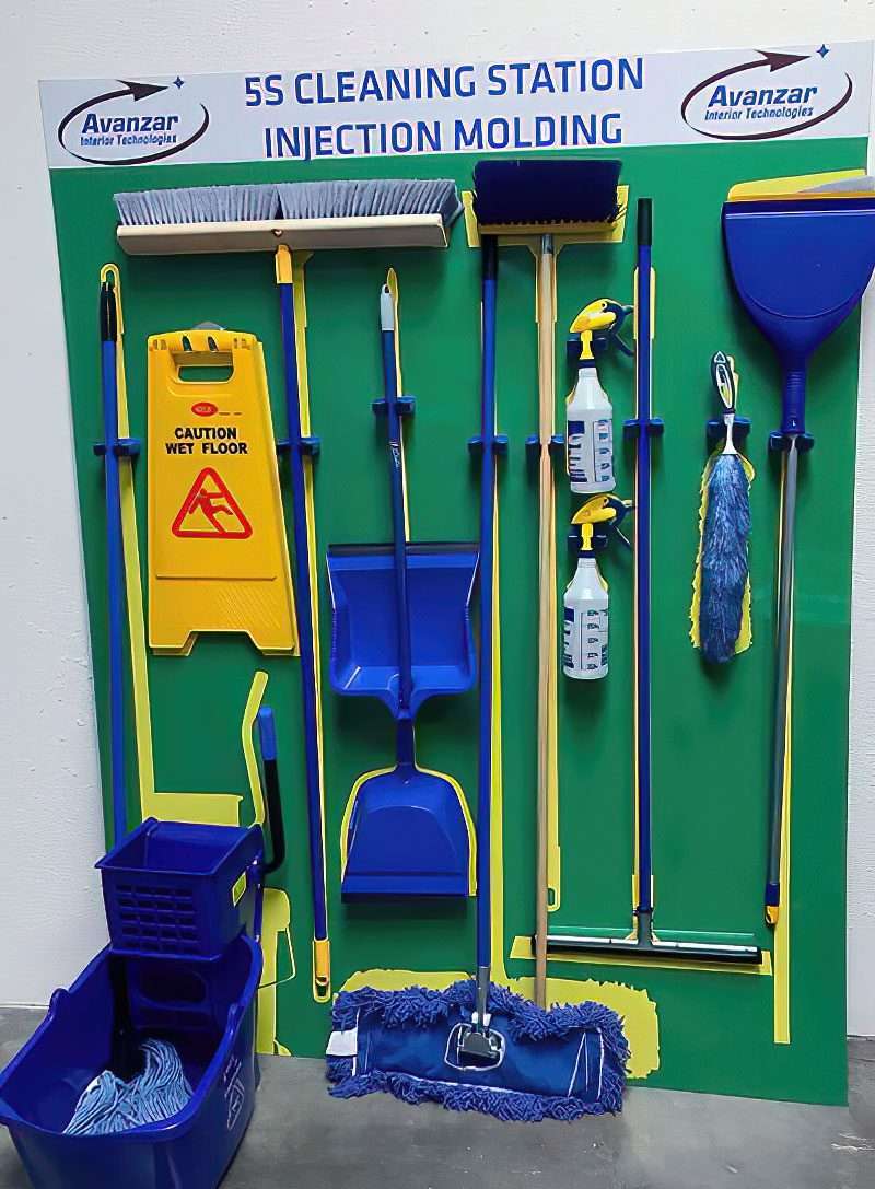 Avanzar Interior Technologies 5S Cleaning Station for Injection Molding with fully loaded brooms, squeegees, duster, dustpans, dual spray bottles, and caution wet floor sign