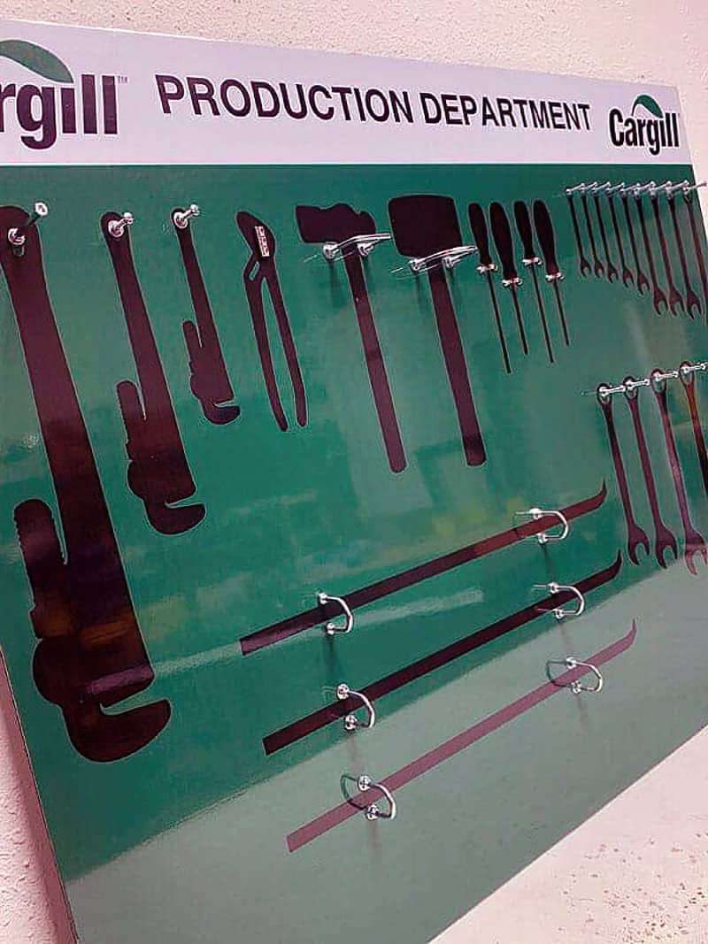 Cargill Production Department green tool shadow board with precision silhouettes and chrome loop hooks for pipe wrenches, pliers, pry bars, and open-end wrenches