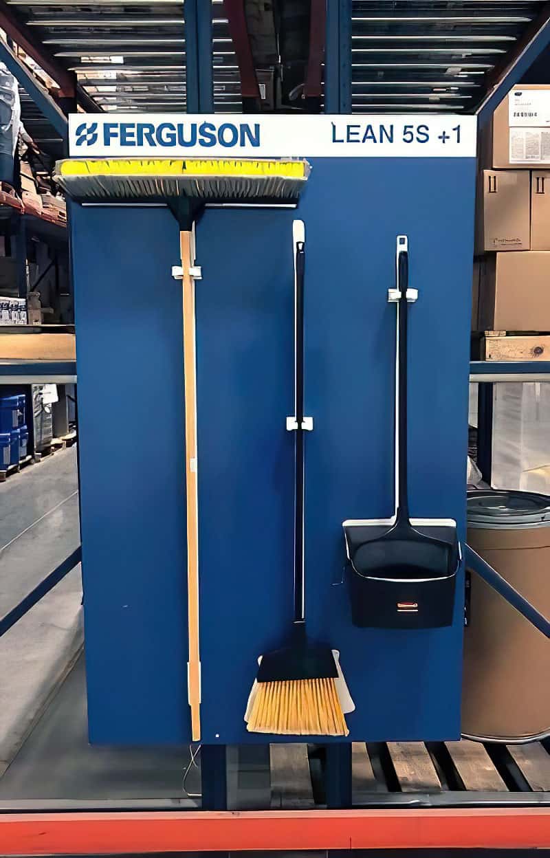 Ferguson Lean 5S plus 1 rack-mounted warehouse cleaning station in dark blue with heavy-duty retention clips for push broom, angle broom, and lobby dustpan