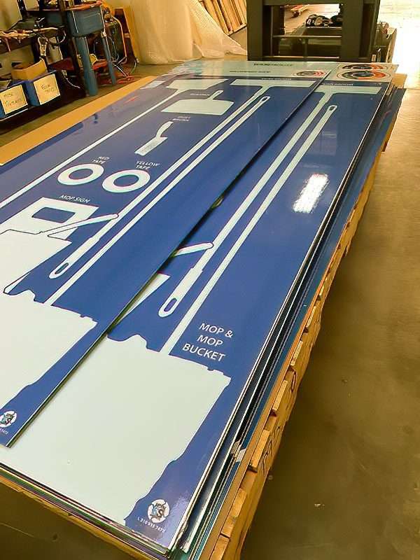 Batch of industrial 5S shadow boards on assembly pallet with white silhouettes for floor squeegee, mop bucket, and caution signs