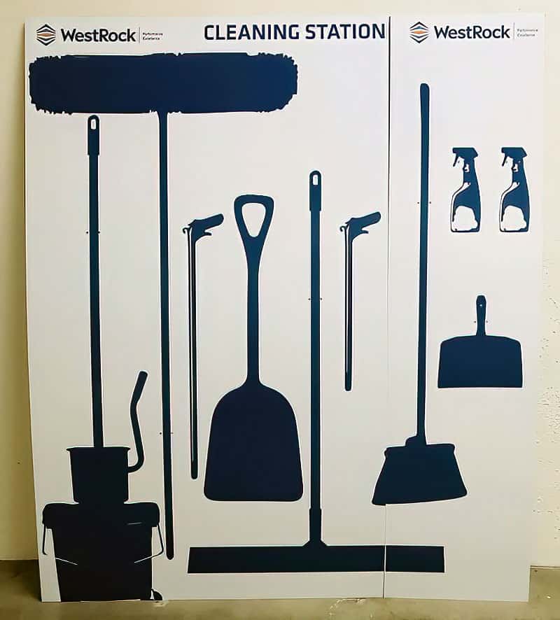 WestRock packaging facility large-format cleaning station shadow board with dark navy silhouettes for mops, shovels, squeegees, and sprayers