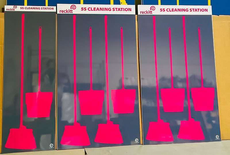 Reckitt 5S Cleaning Station trio of shadow boards with high-contrast fluorescent magenta tool silhouettes for brooms and dustpans