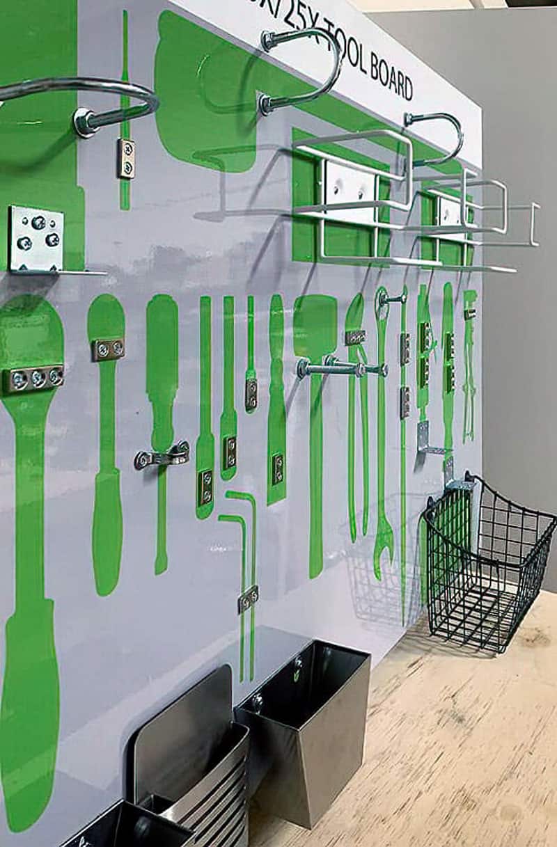 Custom high-density mechanical tool shadow board in bright green with wire baskets, hardware caddies, stainless parts bins, and shadows for ratchets, wrenches, and screwdrivers