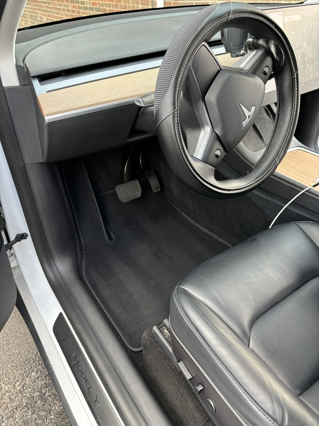 Detailed Tesla cockpit with vacuumed floorboard, pedals, steering wheel, and clean dash console
