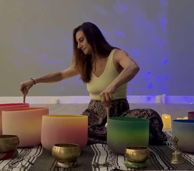 Sara Grossman Crystal Sound Bath Meditation Sara Grossman playing singing crystal sound bowls in a serene candlelit yoga soundbath