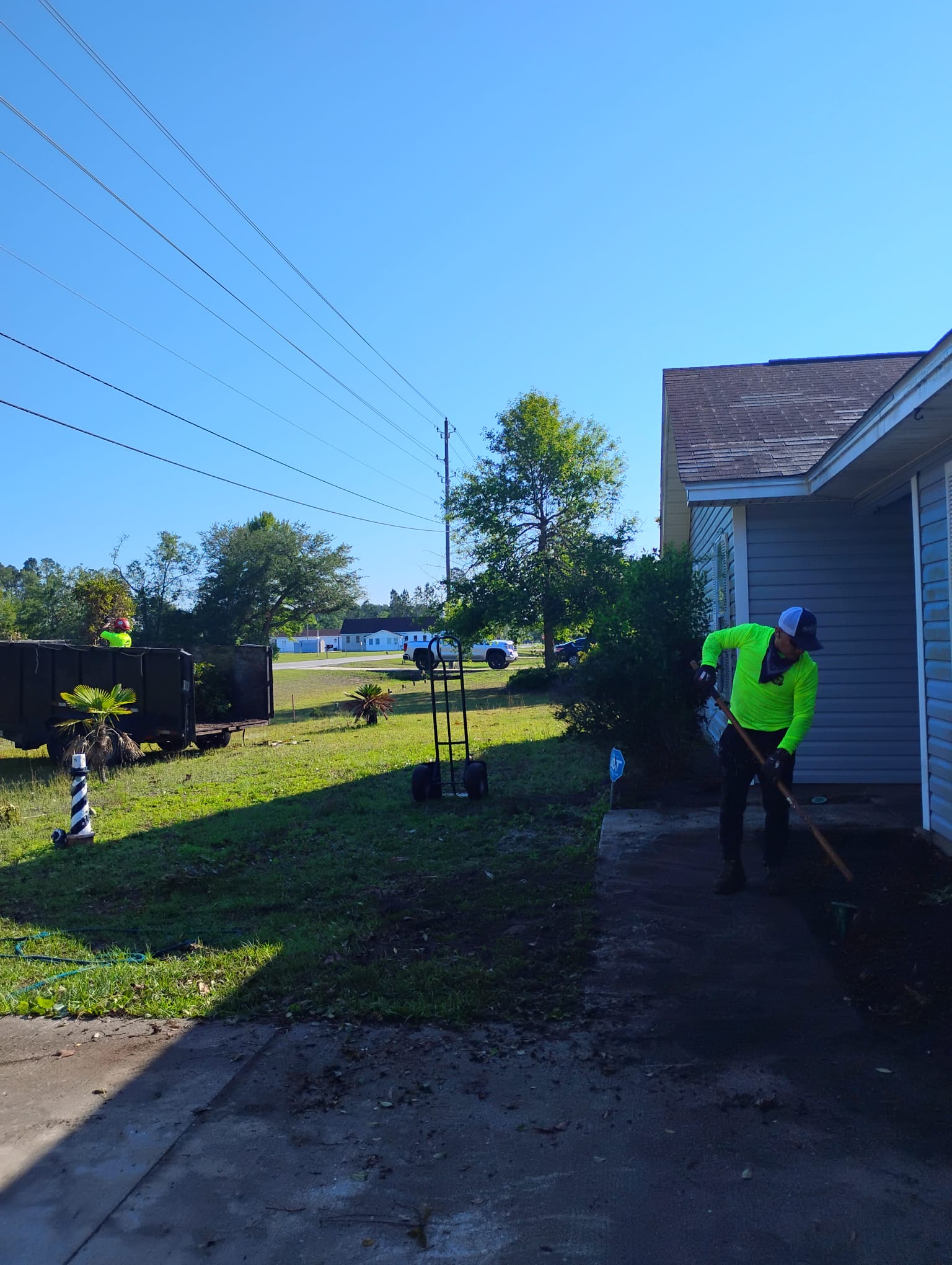 M. & P. Tree Service crew cleaning up residential yard and walkway after tree work in Brunswick GA
