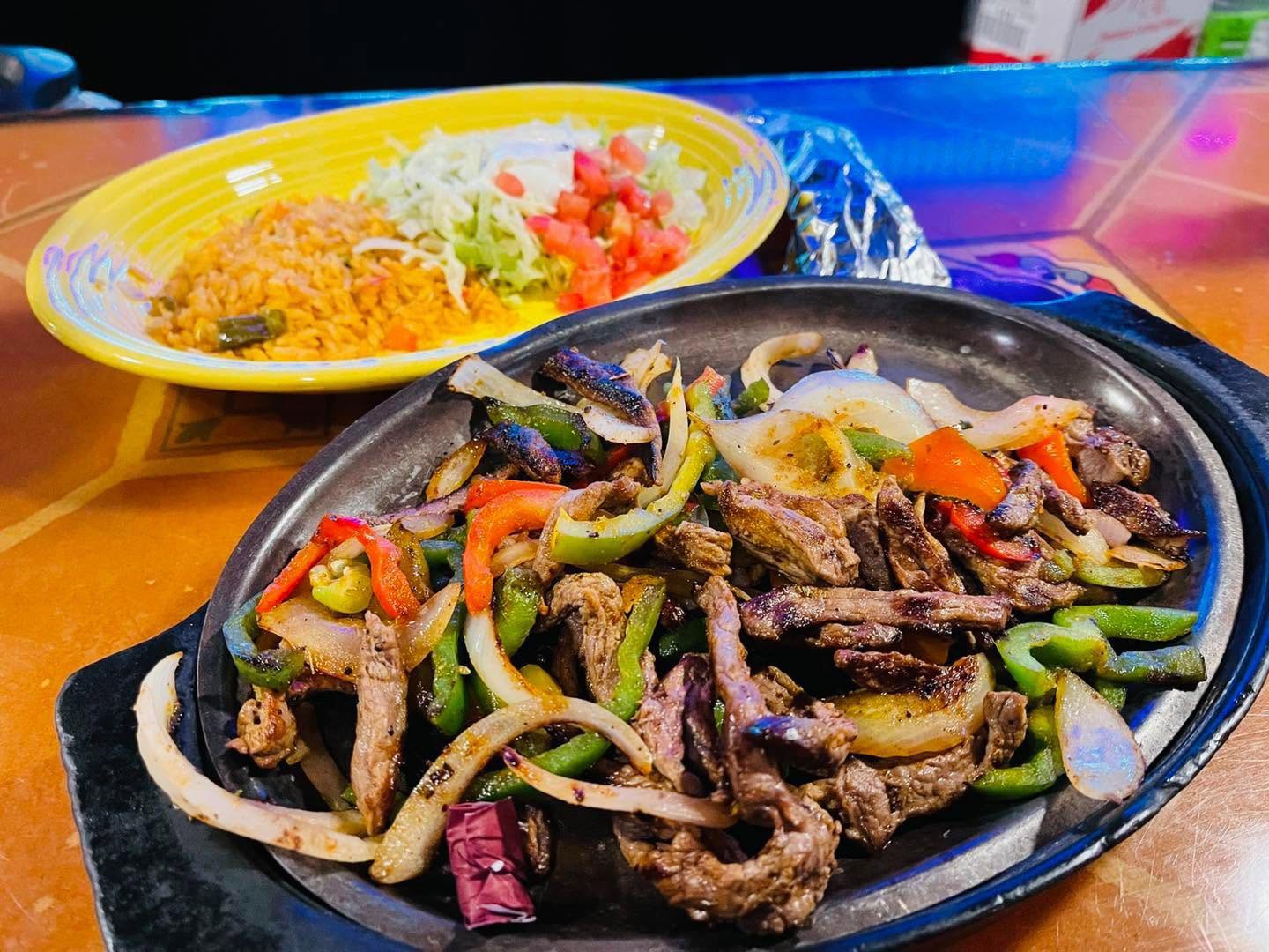 Sizzling cast-iron steak fajitas served with Mexican rice and salad