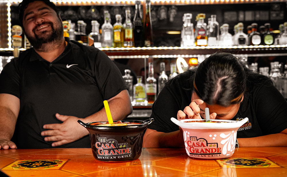 Guests laughing and enjoying refreshing drinks from custom Casa Grande clay bowls at the Stellhorn Road full bar