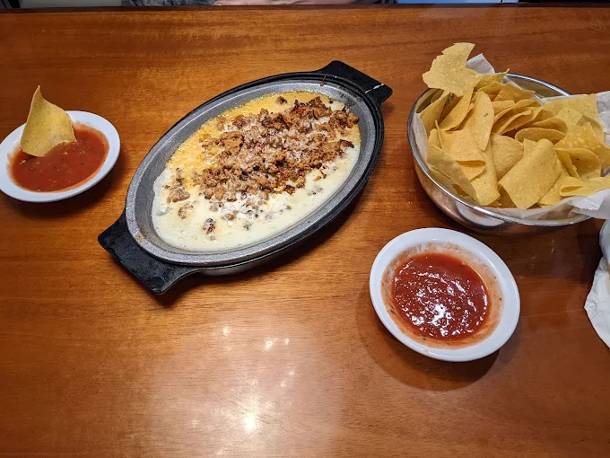 Sizzling skillet of choriqueso cheese dip served with fresh tortilla chips and house salsa at Casa Grande Hicksville