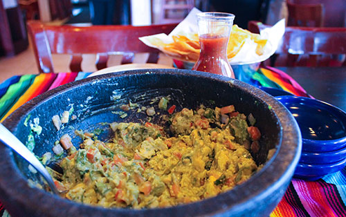 Signature fresh guacamole served in an authentic volcanic stone molcajete with warm tortilla chips and salsa at Casa Grande Mexican Grill
