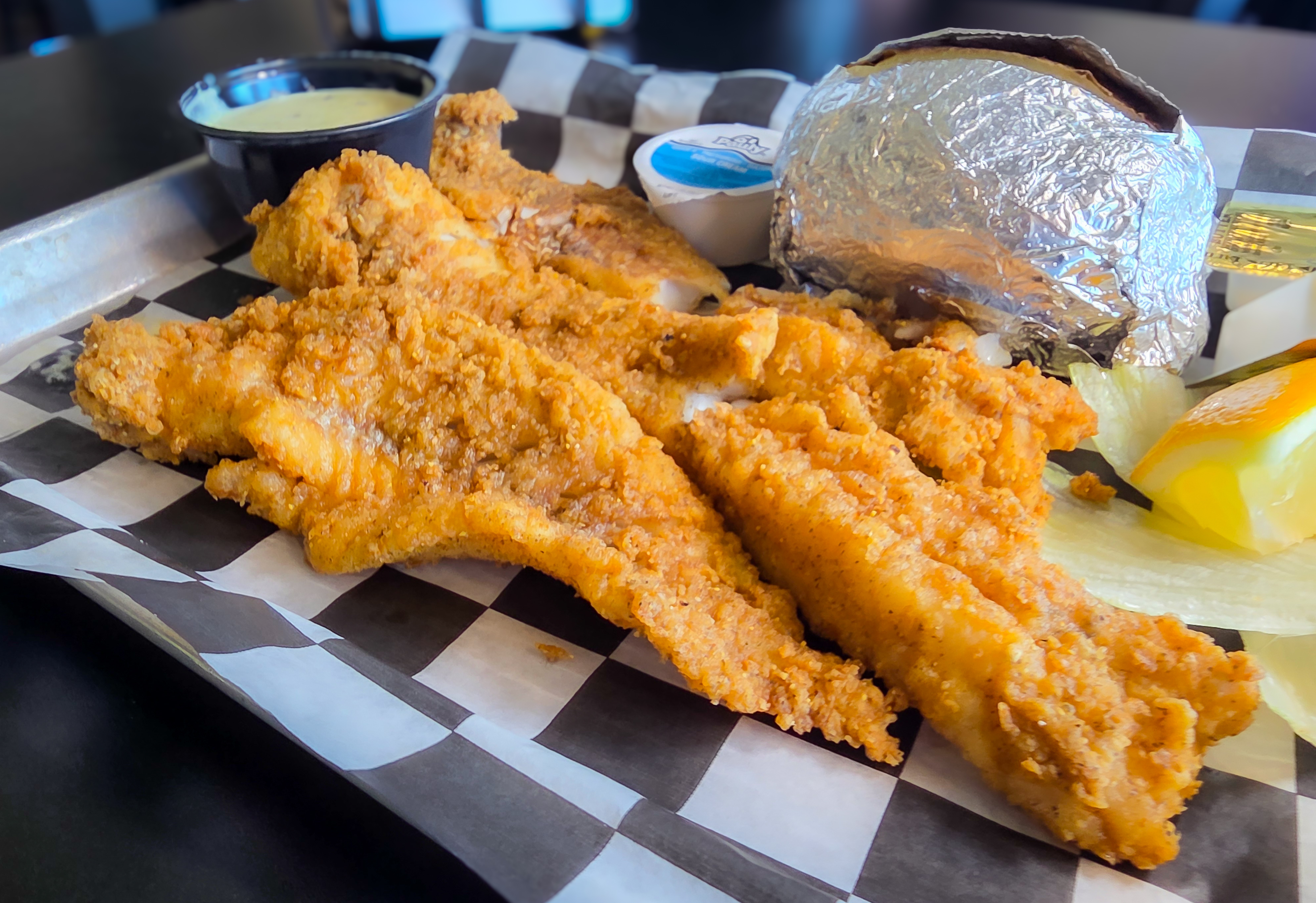 Crispy hand-breaded golden fish fillets served with baked potato tartar sauce and lemon wedge