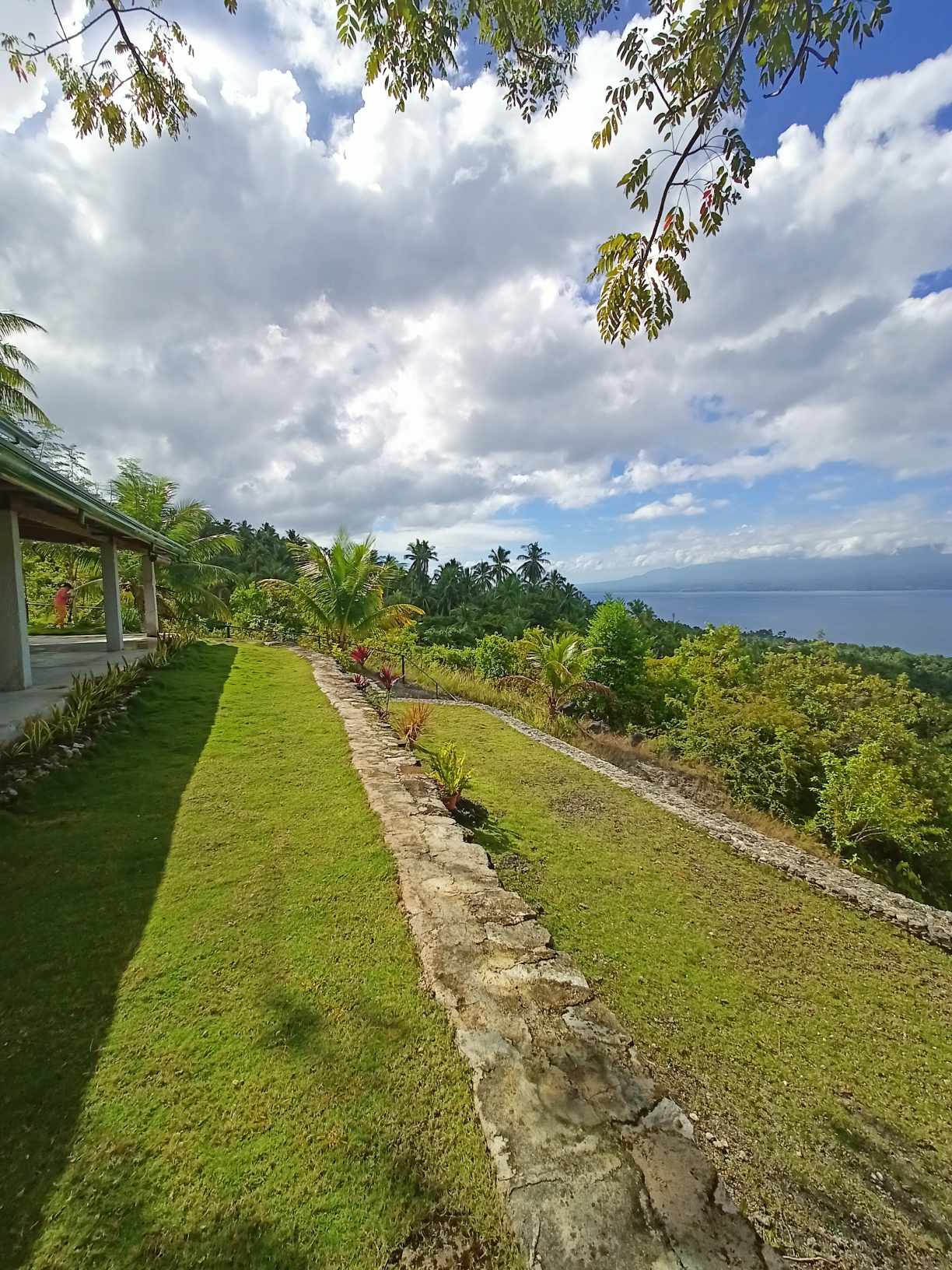 Curved stone retaining wall along the manicured lawn with sweeping views toward the southern coastline