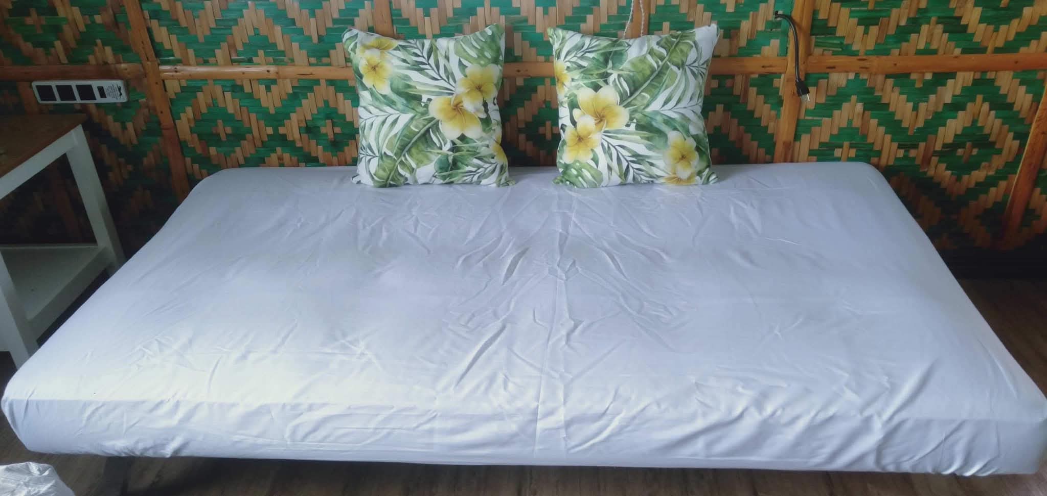 Comfortable daybed with tropical plumeria cushions against the woven amakan bamboo wall at Mims House Cebu