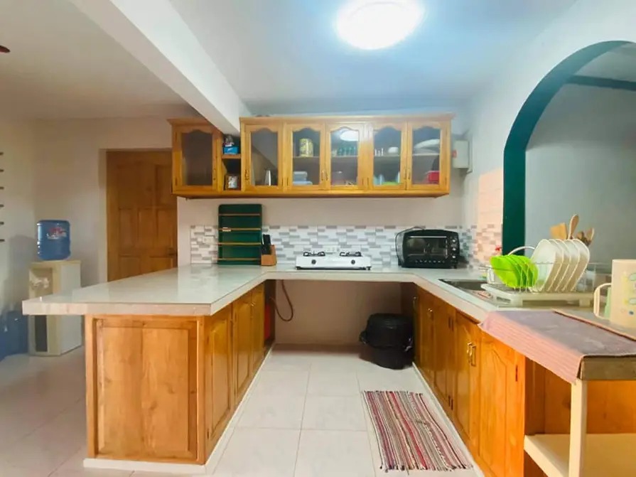 Full kitchen at Mims House Cebu with wood cabinets, countertop bar, gas stove, and water dispenser