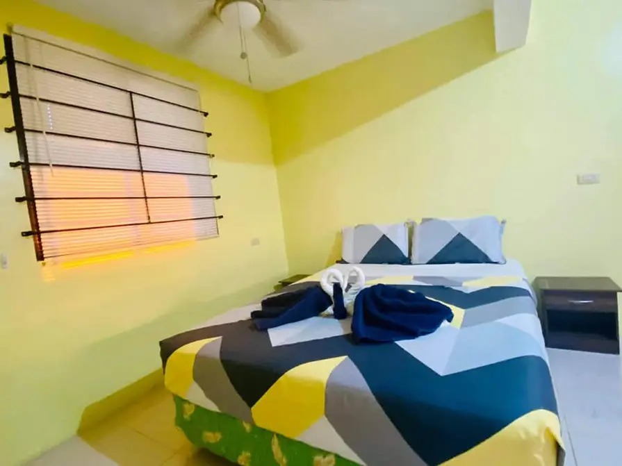 Furnished bedroom at Mims House Cebu with double bed, decorative towel origami, ceiling fan, and window blinds