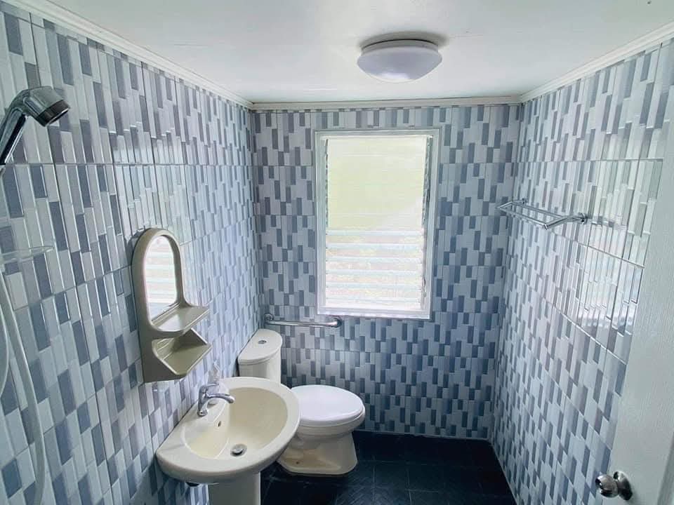 Clean tiled bathroom at Mims House Cebu with blue and grey mosaic tiles, pedestal sink, mirror, and shower