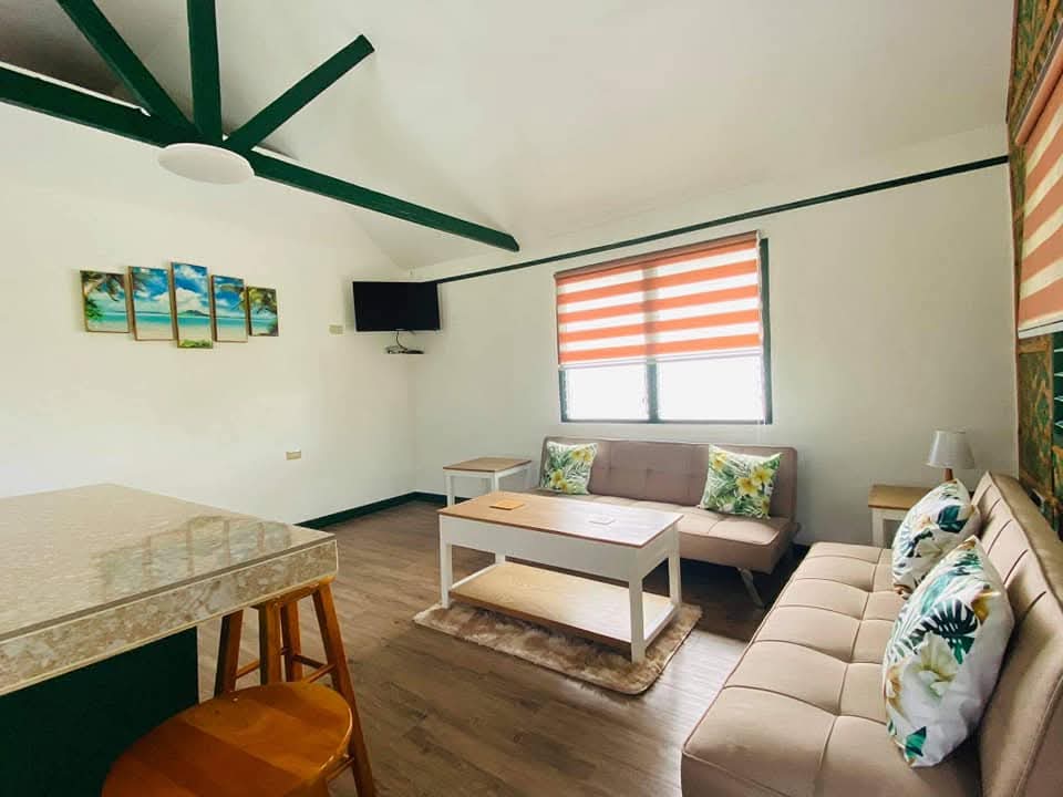 Vaulted ceiling living lounge with timber beams, sofas, coffee table, and breakfast bar at Mims House Cebu
