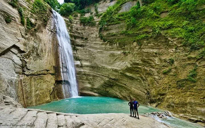 Dao Falls cascading down towering curved limestone canyon walls into a natural pool