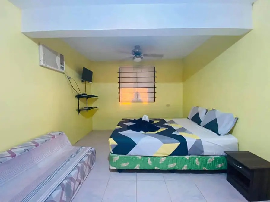 Air-conditioned bedroom at Mims House Cebu with wall TV and ceiling fan