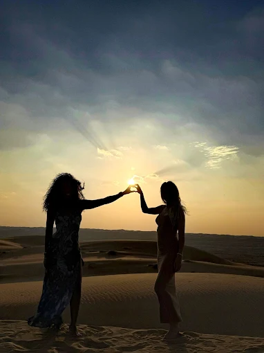 Friends connecting hands against the setting desert sun