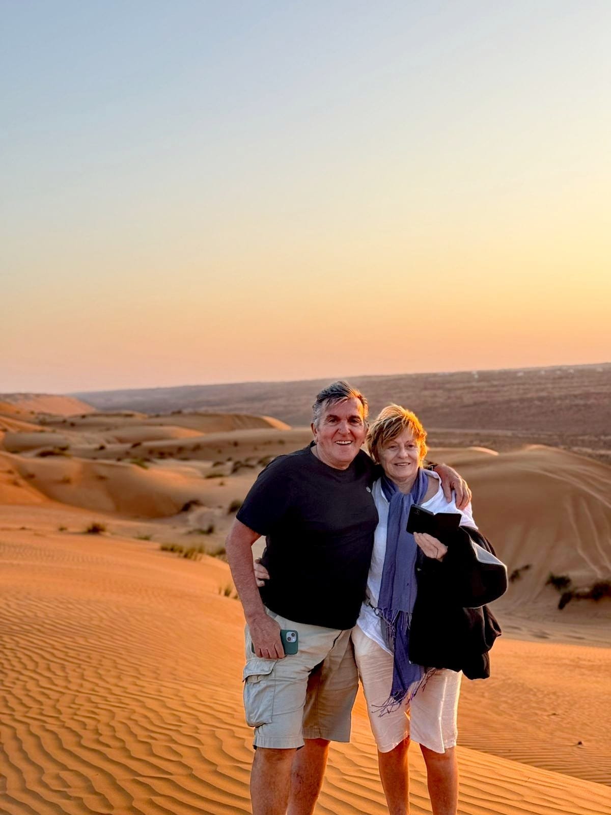 Couple standing on the dune ridge enjoying the sunset view