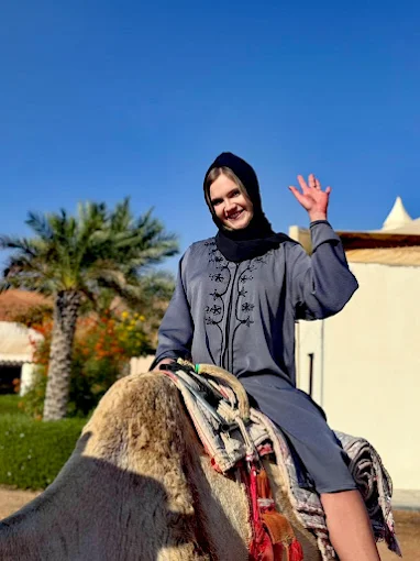 Waving guest enjoying a traditional camel ride experience