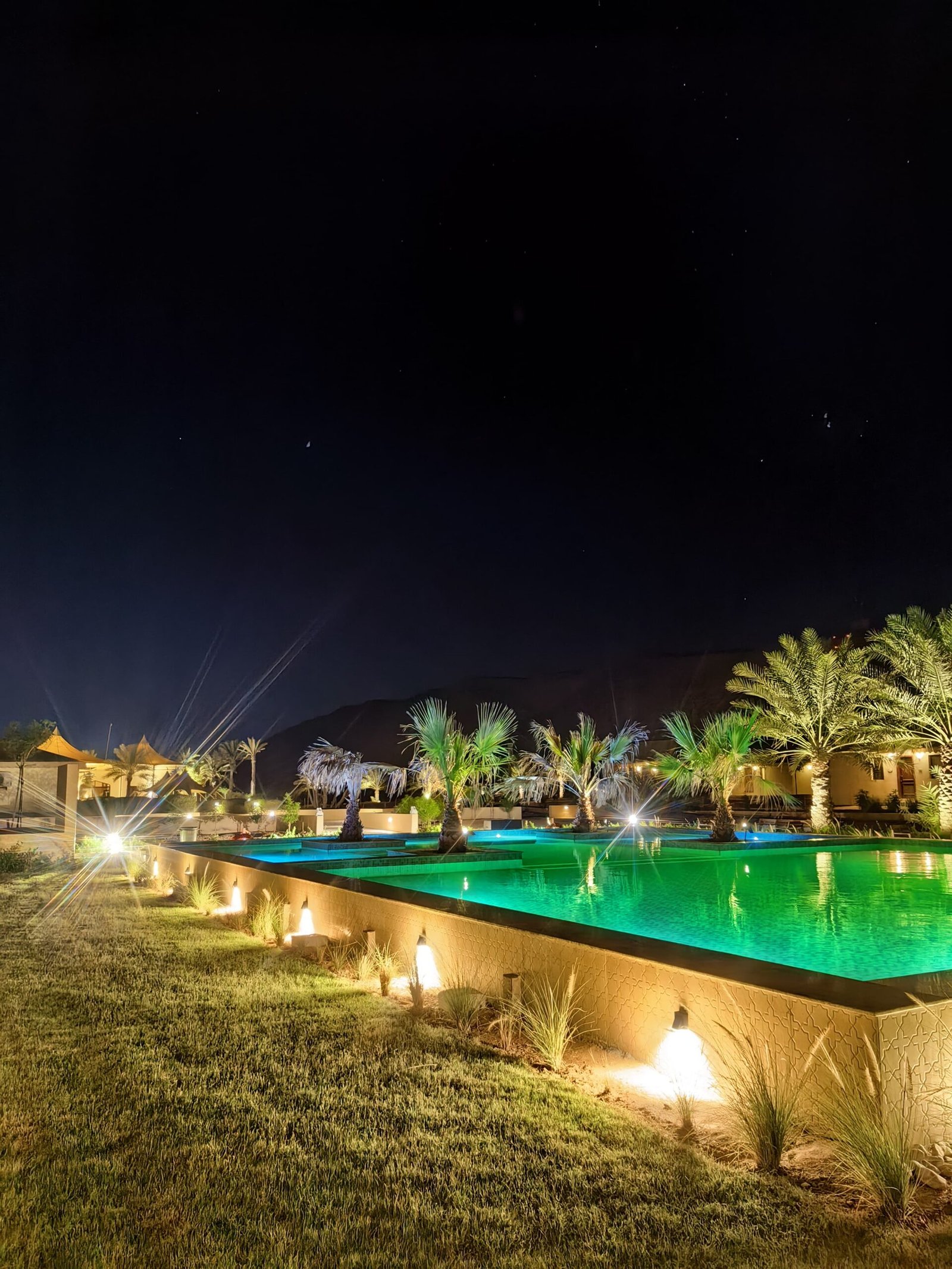Night view of illuminated swimming pool and surrounding resort grounds