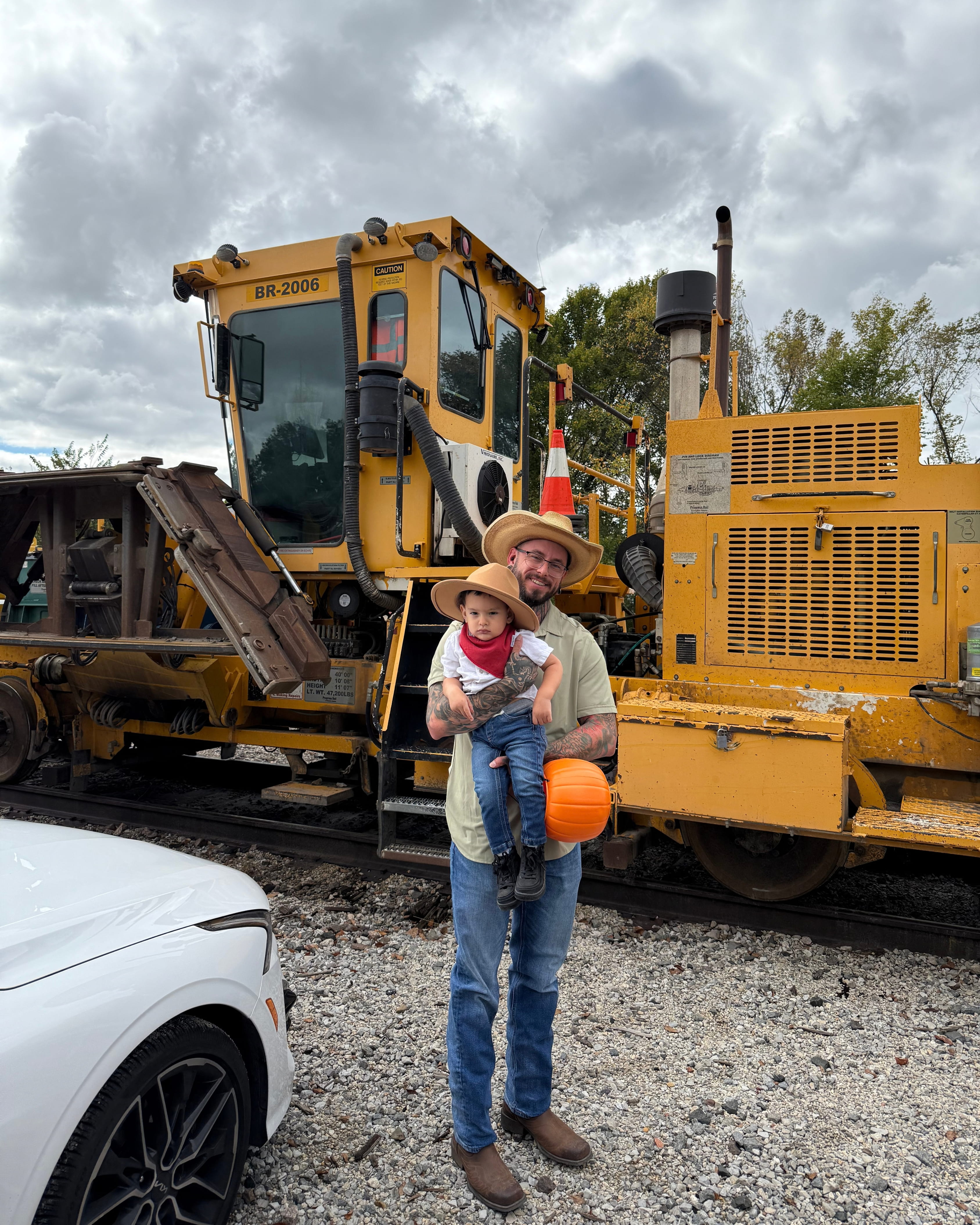 Sam Rodriguez with his son in front of heavy railroad equipment