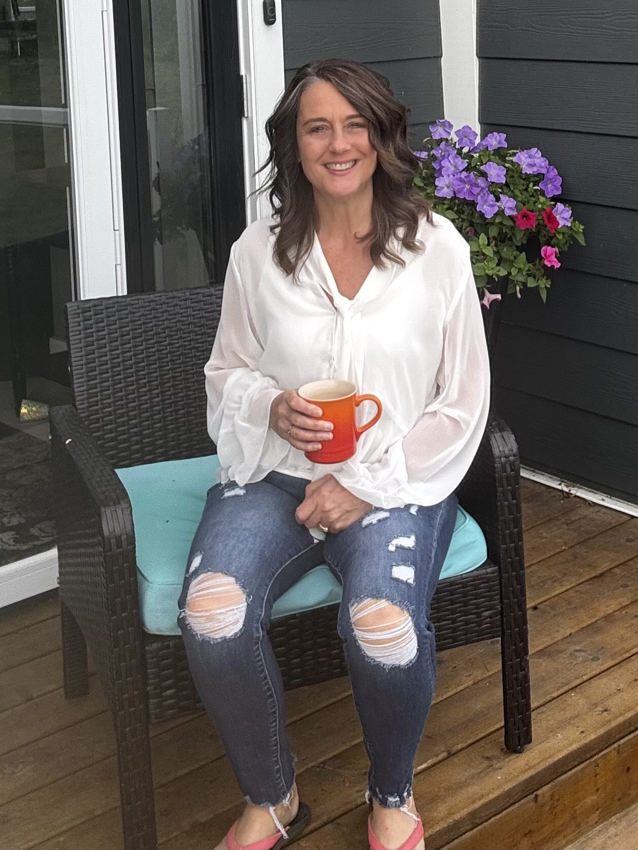 Portrait of Lori sitting on her porch with a warm cup