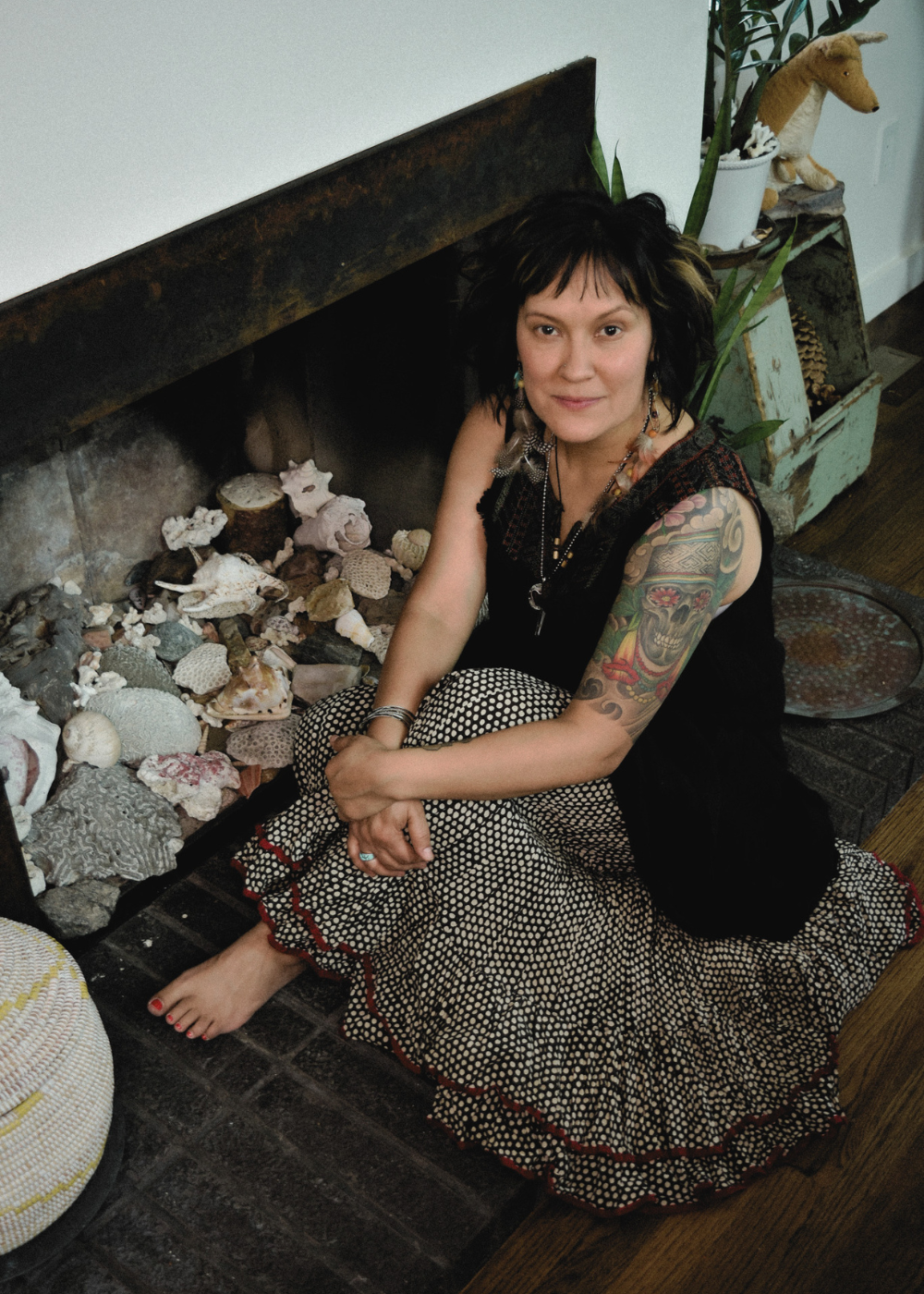 Joaquina Mascuch seated peacefully by fireplace with shells and ceremonial stones
