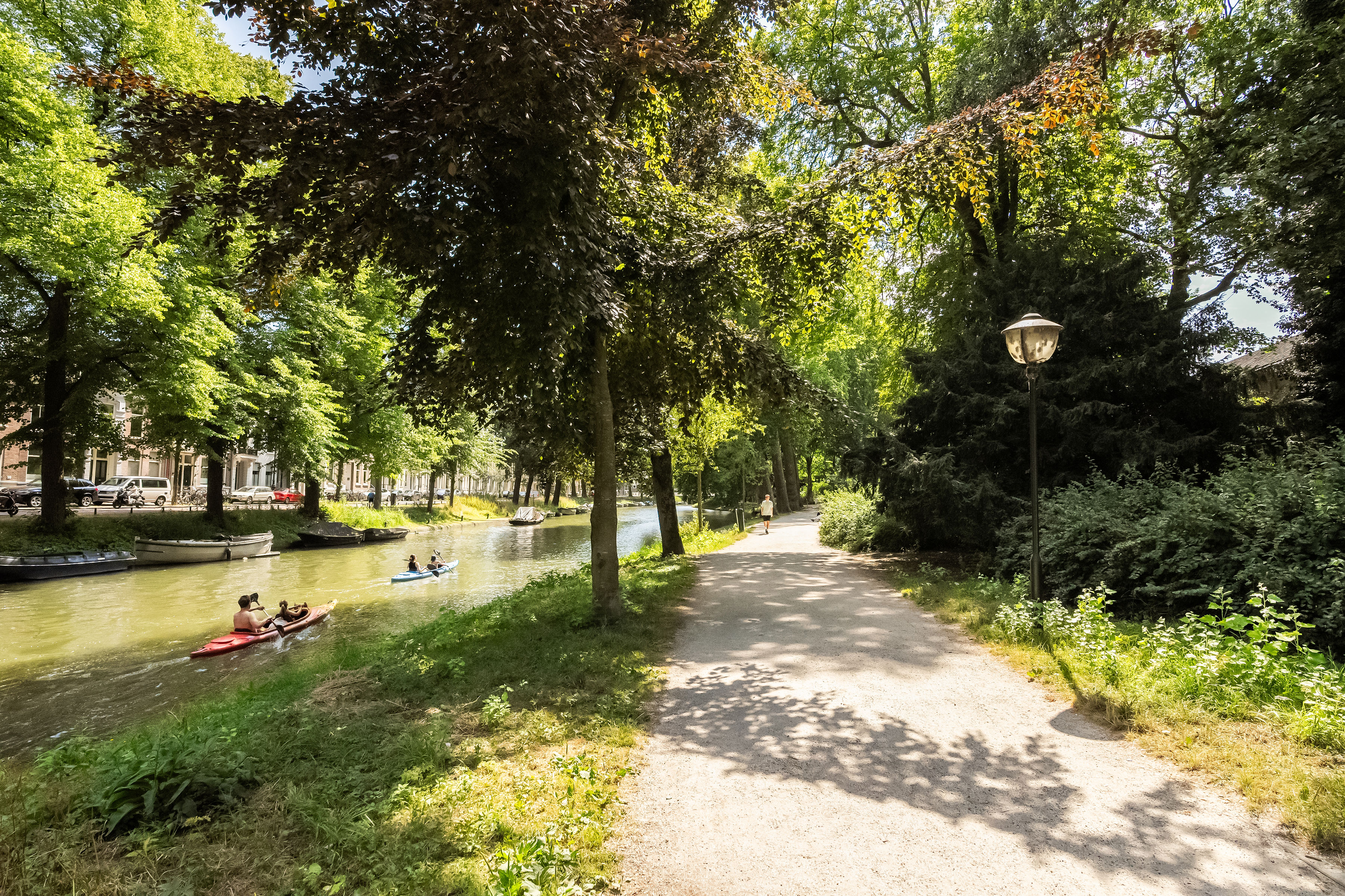 Zonnige Utrechtse singel met kanovaarders en weelderig groen wandelpad