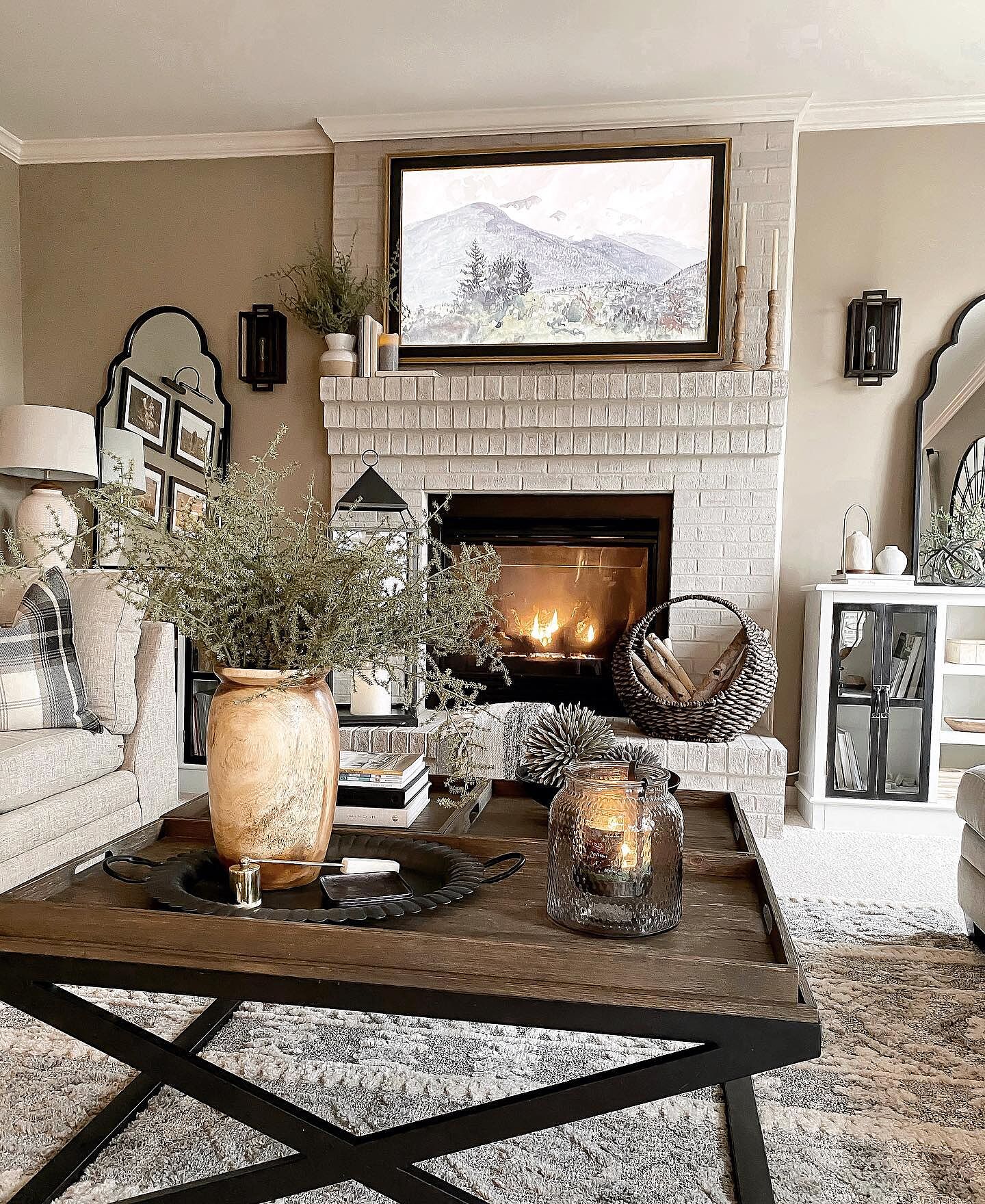 Samsung Frame TV installed above a painted brick fireplace mantel displaying majestic mountain landscape art in a warm, inviting living room.