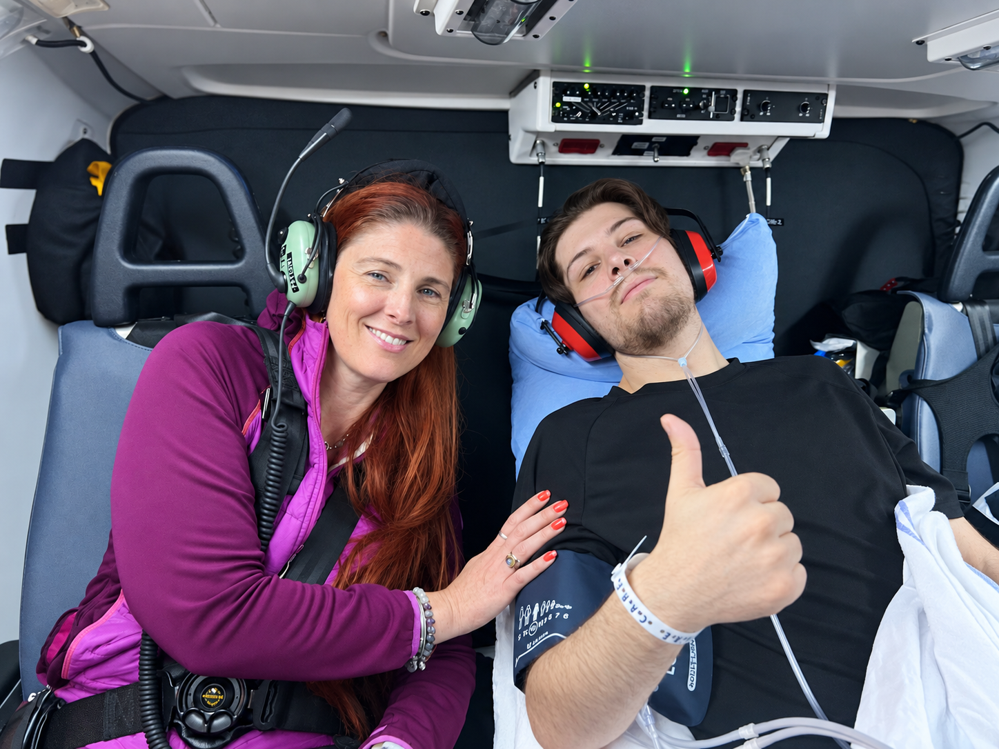 Harmony and Winston on the medical flight, wearing headsets and Winston giving a thumbs up