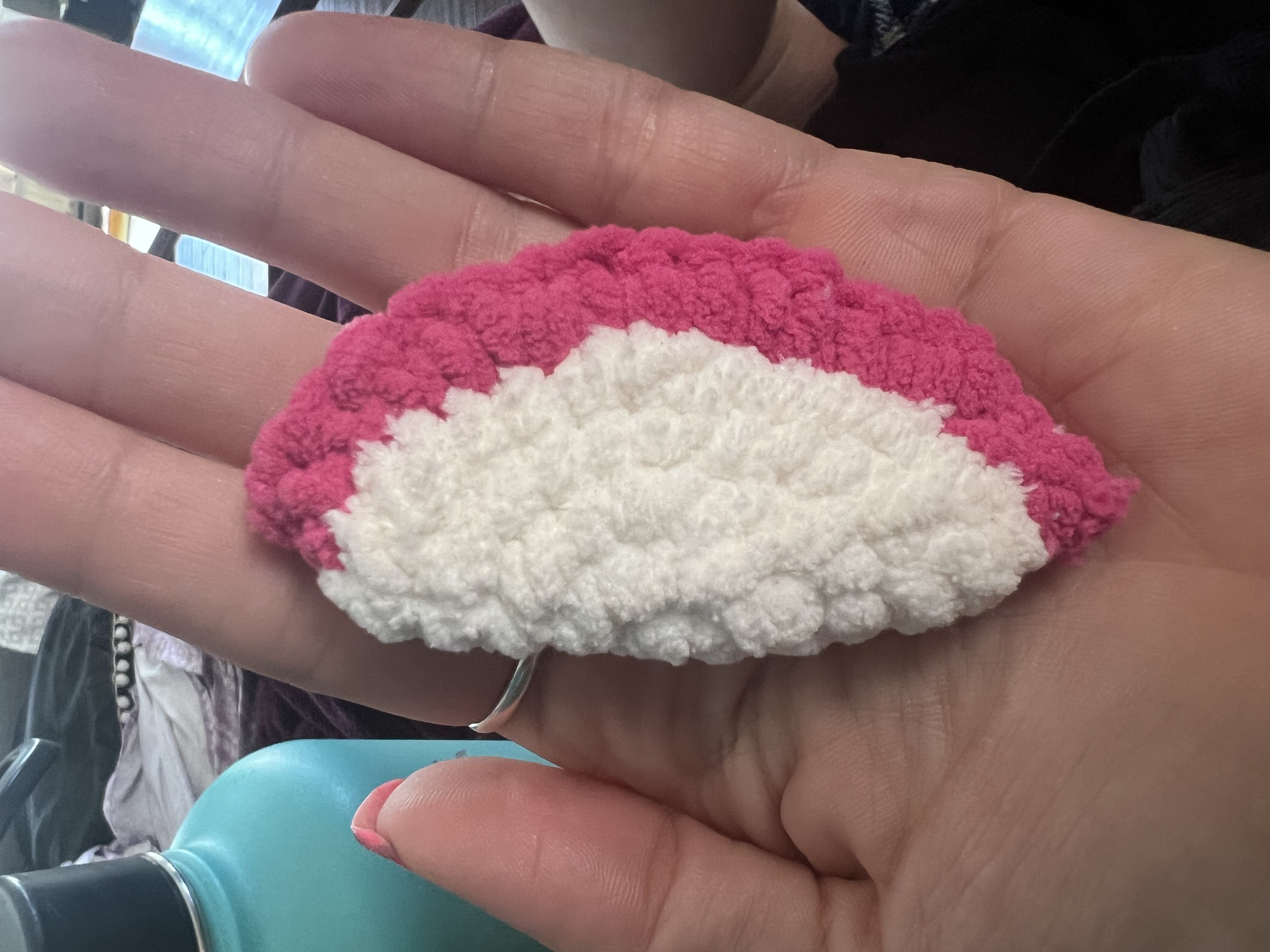 The first single dragon fruit crochet flipper being held in a hand
