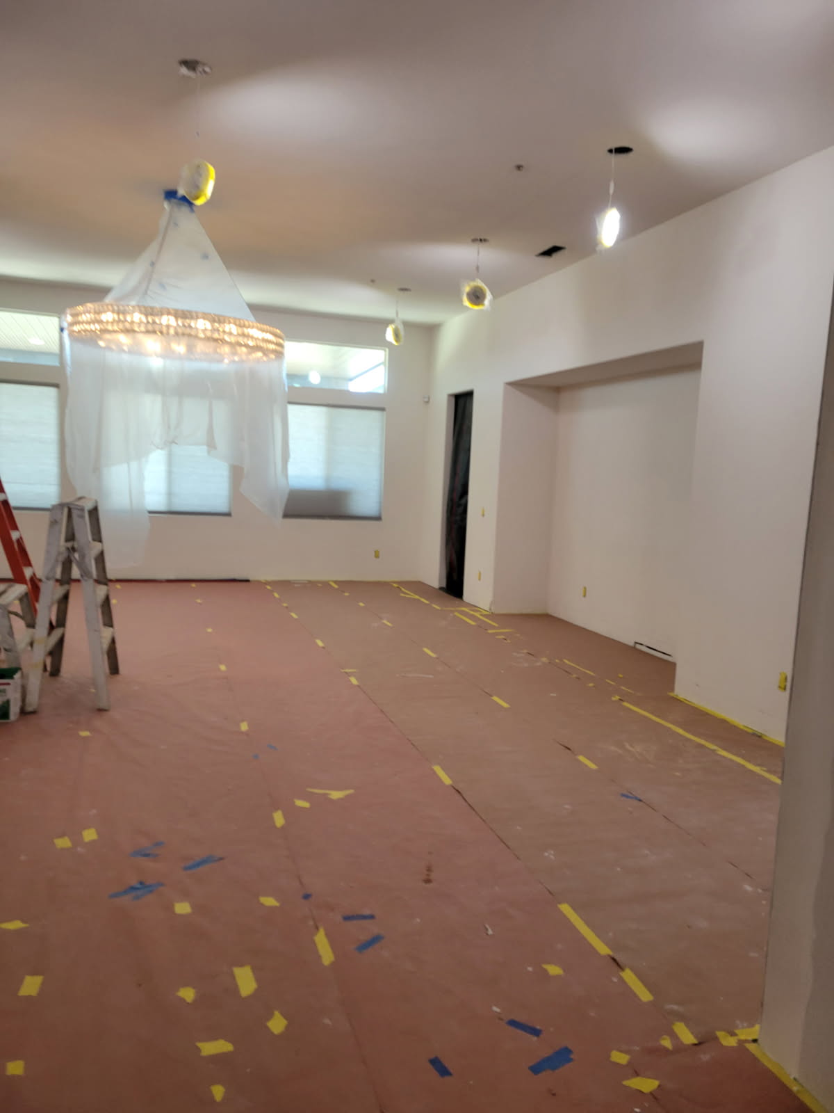 Finished interior great room walls and ceiling with protected chandelier and clean lines