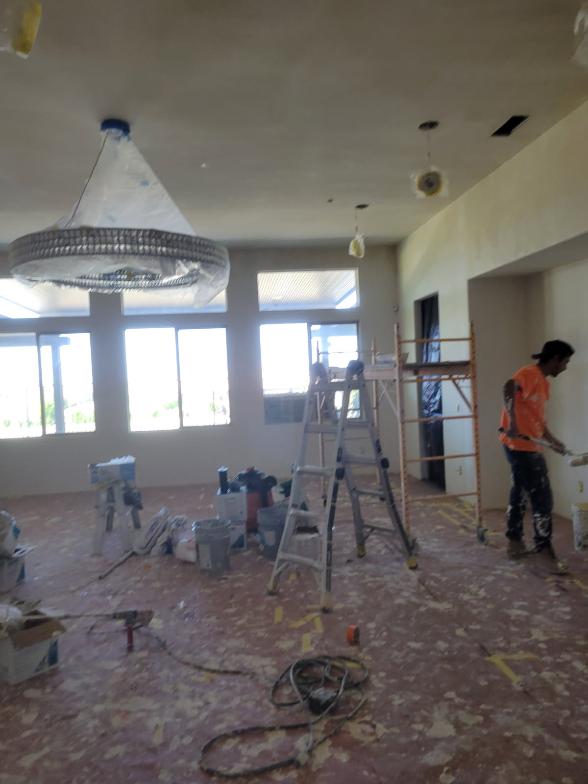 Mario's crew prepping and rolling interior drywall paint with scaffolding and floor masking