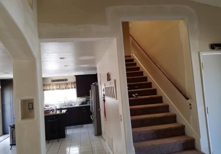 Smooth drywall taping and pass-through archway repair framed by staircase